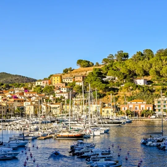 Blick auf bunte Häuser und Segelyachten im Hafen von Porto Azzurro auf der Insel Elba, Toskana, Italien