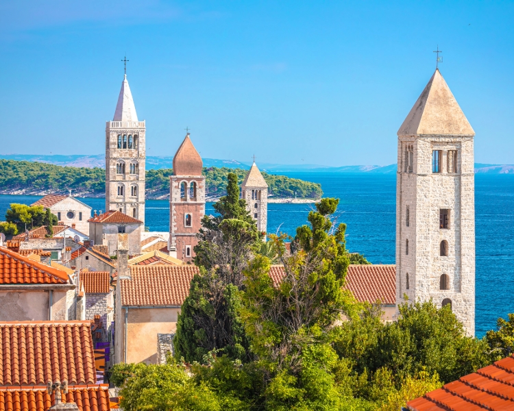 Historische Altstadt von Rab mit vier markanten Kirchtürmen und Blick aufs Meer