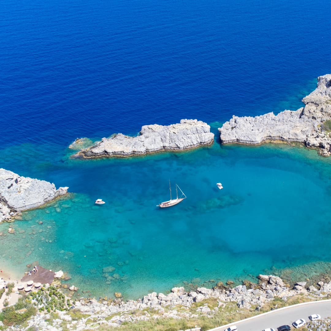 Segelboot vor Anker in einer geschützten Bucht mit türkisblauem Wasser bei Rhodos im Dodekanes, Griechenland