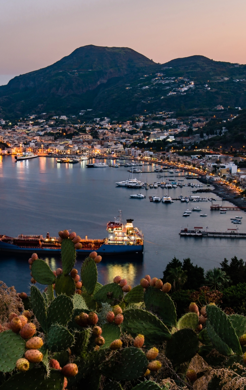 Blick auf die Marina und Altstadt von Lipari bei Sonnenuntergang mit Segelyachten im Hafen – Yachtcharter mit BlackSails-Yachting
