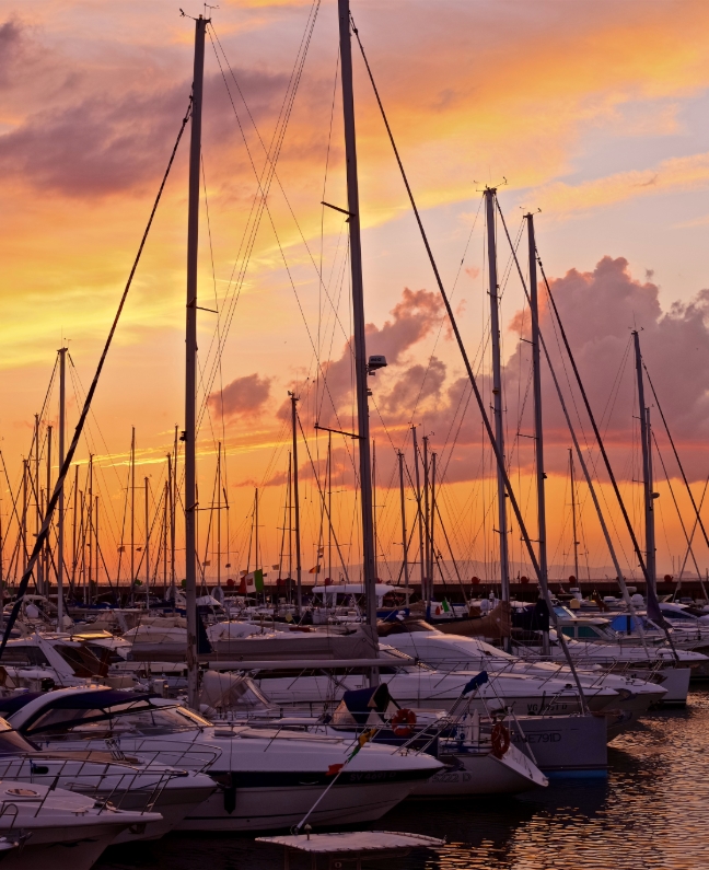 Segelyachten in der Marina bei Sonnenuntergang – Rückkehr nach einer Yachtcharter mit BlackSails-Yachting in der Toskana