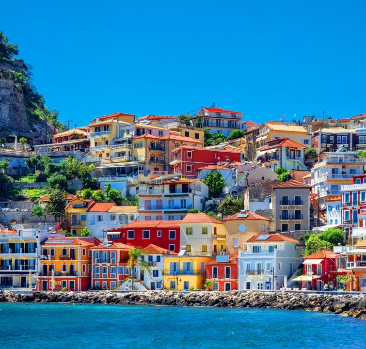 Bunte Häuserfassaden an der Uferpromenade von Parga, Griechenland – Blick vom Ankerplatz beim Yachtcharter mit BlackSails-Yachting im Ionischen Meer