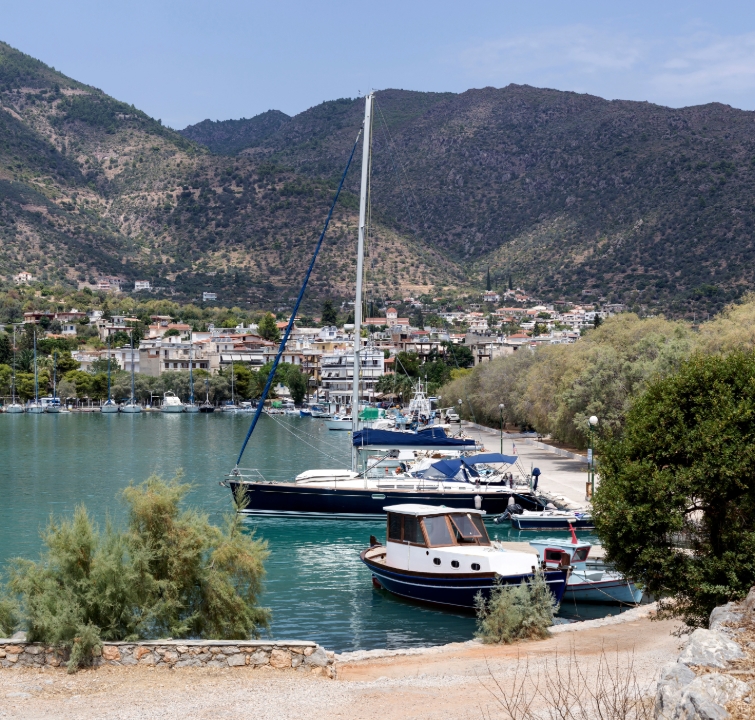 Yachten im ruhigen Hafen von Methana mit Blick auf das griechische Festland – idealer Stopp beim Yachtcharter mit BlackSails-Yachting