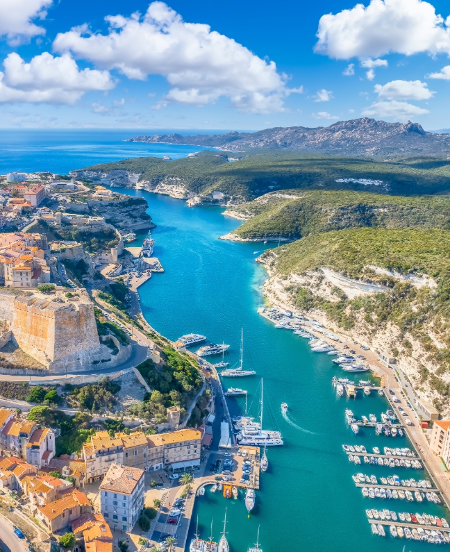 Luftaufnahme der Hafenbucht von Bonifacio mit Yachten, Altstadt und Felsküste – Etappenziel bei einer Yachtcharter mit BlackSails-Yachting