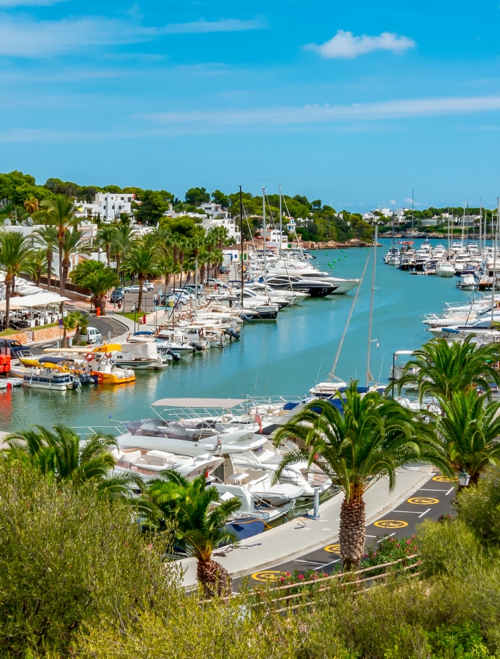 Blick auf die Marina Cala d’Or auf Mallorca – Yachten, Palmen und weiße Häuser entlang eines geschützten Hafenkanals. Perfekt für Yachtcharter mit BlackSails-Yachting.