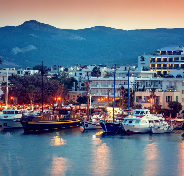 Abendstimmung in der Marina Kos mit festgemachten Yachten und Blick auf die umliegenden Berge – Startpunkt vieler Yachtcharter-Törns mit BlackSails-Yachting im Dodekanes.