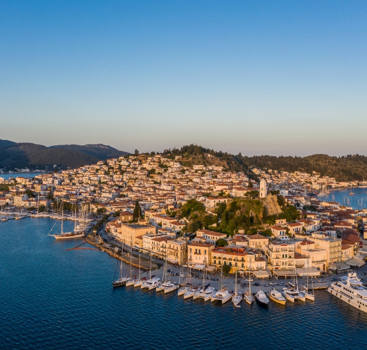 Luftaufnahme von Poros mit dicht bebautem Stadtberg und voll belegtem Stadthafen – Ziel beim Yachtcharter mit BlackSails-Yachting