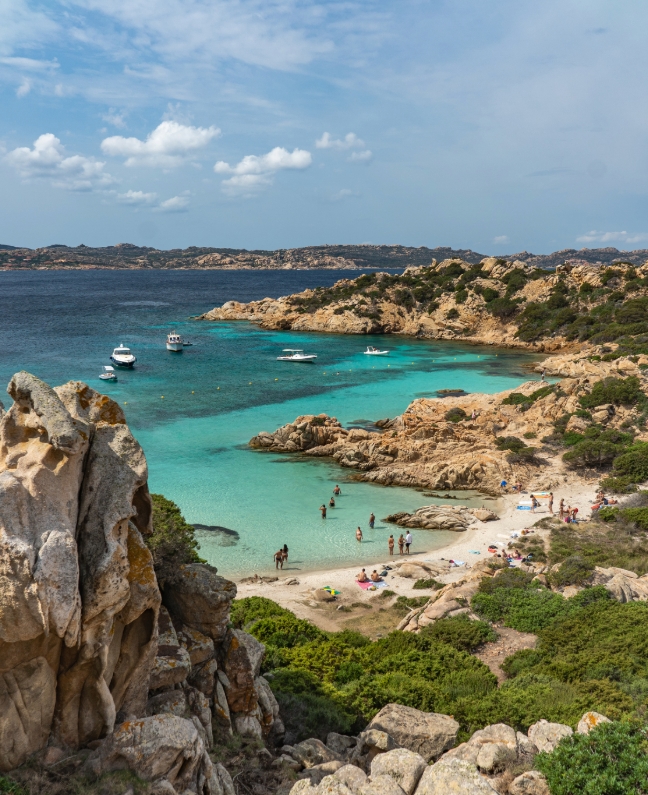 Boote und Badegäste in der Bucht von Porto Palma auf Caprera – Ankerplatz bei einer Yachtcharter mit BlackSails-Yachting