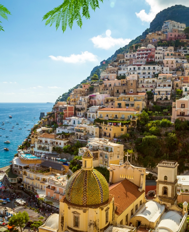 Blick auf Positano an der Amalfiküste mit bunten Häusern am Hang und Booten im türkisblauen Meer – perfektes Ziel beim Yachtcharter mit BlackSails-Yachting