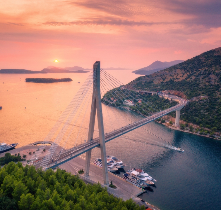 Sonnenuntergang über der Franjo-Tuđman-Brücke in Dubrovnik mit Yachten im Vordergrund – Rückkehr zum Ausgangspunkt beim Yachtcharter Süddalmatien mit BlackSails-Yachting