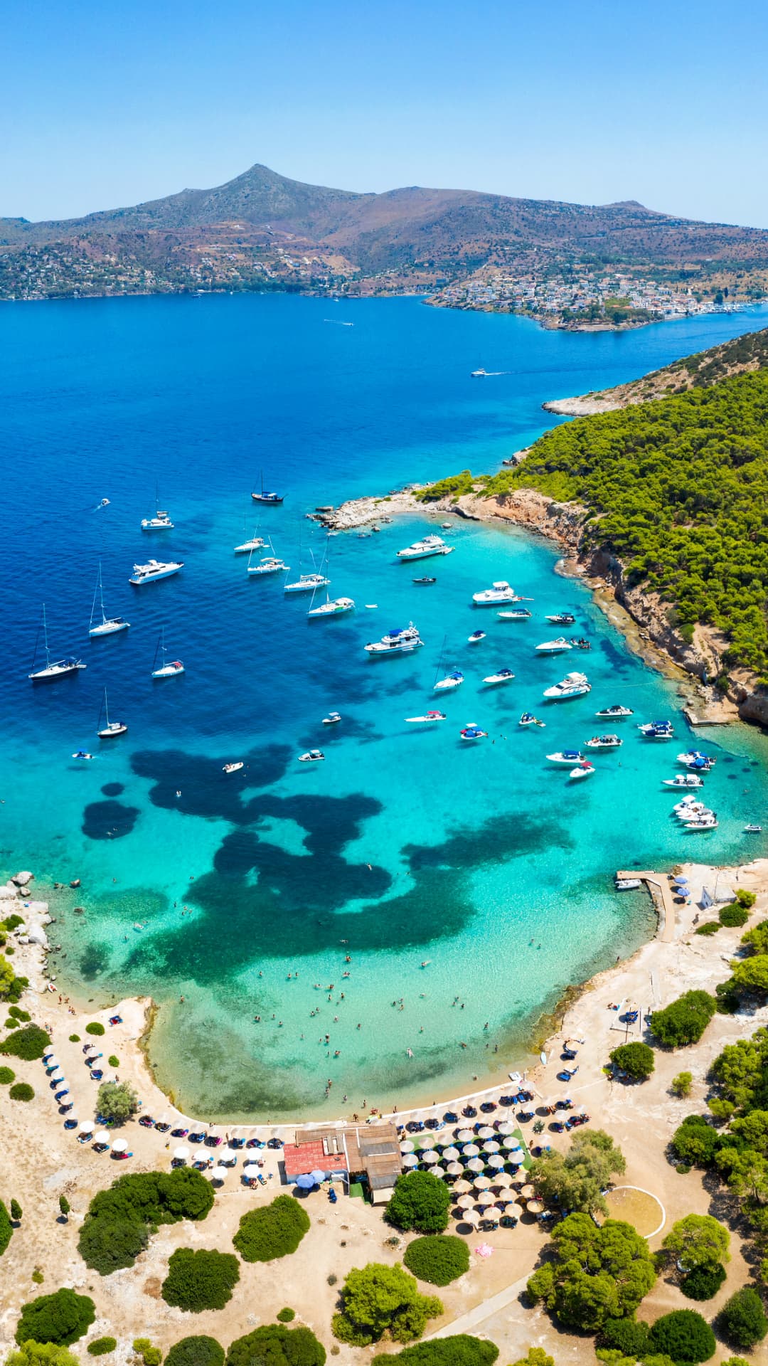 Traumbucht mit türkisfarbenem Wasser, Yachten und Badegästen im Saronischen Golf – Segelrevier für Yachtcharter mit BlackSails-Yachting