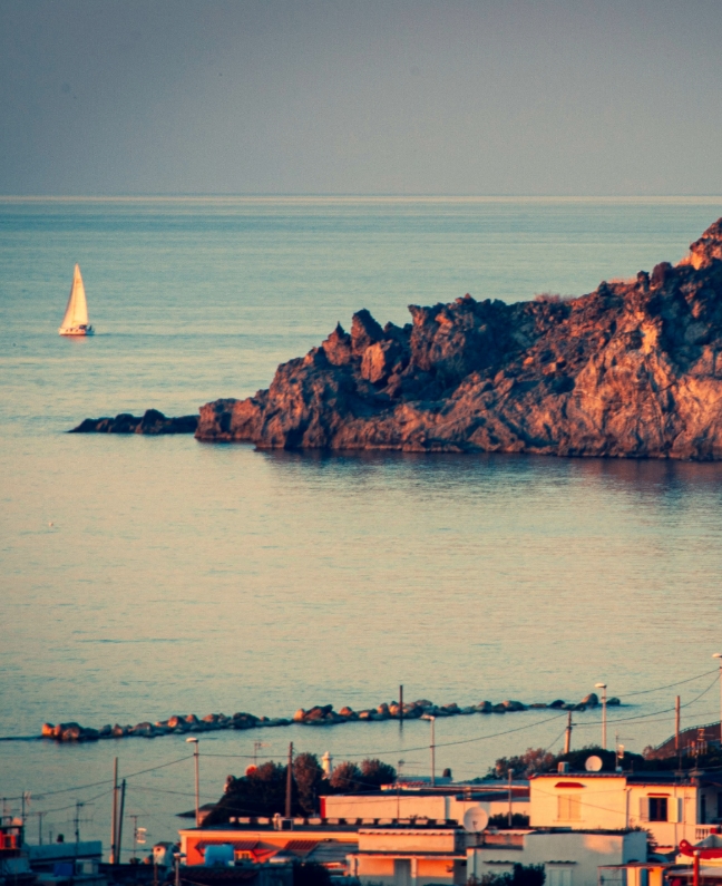 Einzelnes Segelboot vor der Küste von Ischia bei Sonnenuntergang – ruhiger Moment beim Yachtcharter mit BlackSails-Yachting