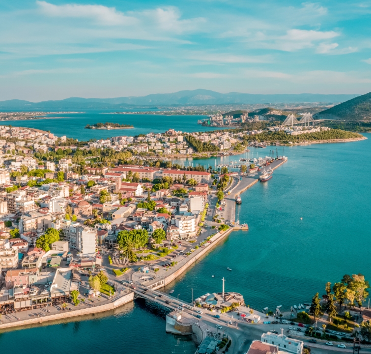 Luftaufnahme eines griechischen Küstenorts mit Hafenanlage, Brücken und türkisfarbenem Wasser – Start- oder Zwischenstation beim Yachtcharter mit BlackSails-Yachting.