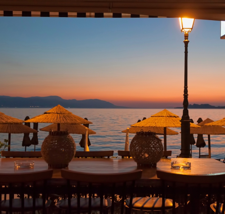 Abendstimmung am Meer mit Laternenlicht, Strohschirmen und sanftem Wellengang – perfekter Tagesausklang beim Yachtcharter mit BlackSails-Yachting.