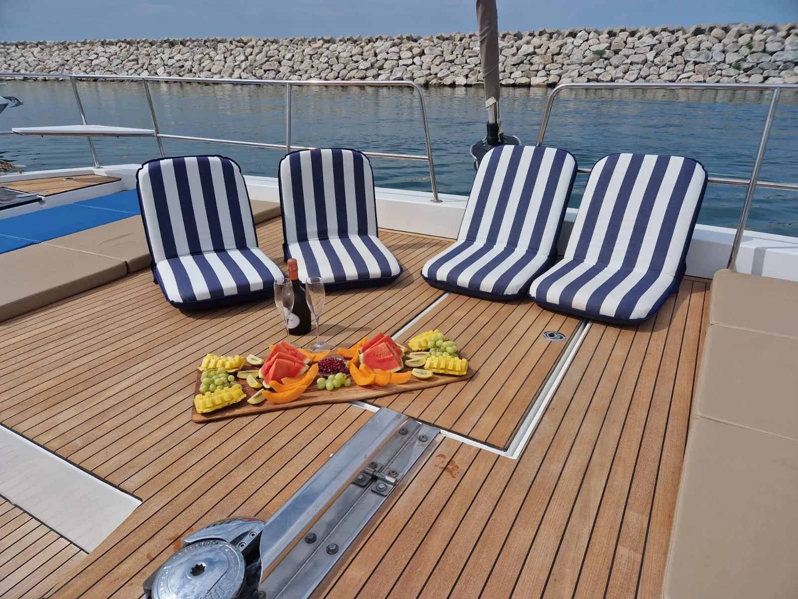 Genuss an Deck der Bali 5.4 – Champagner und frische Früchte, stilvoll serviert von der Crew während Ihres exklusiven Segeltörns auf Ibiza.