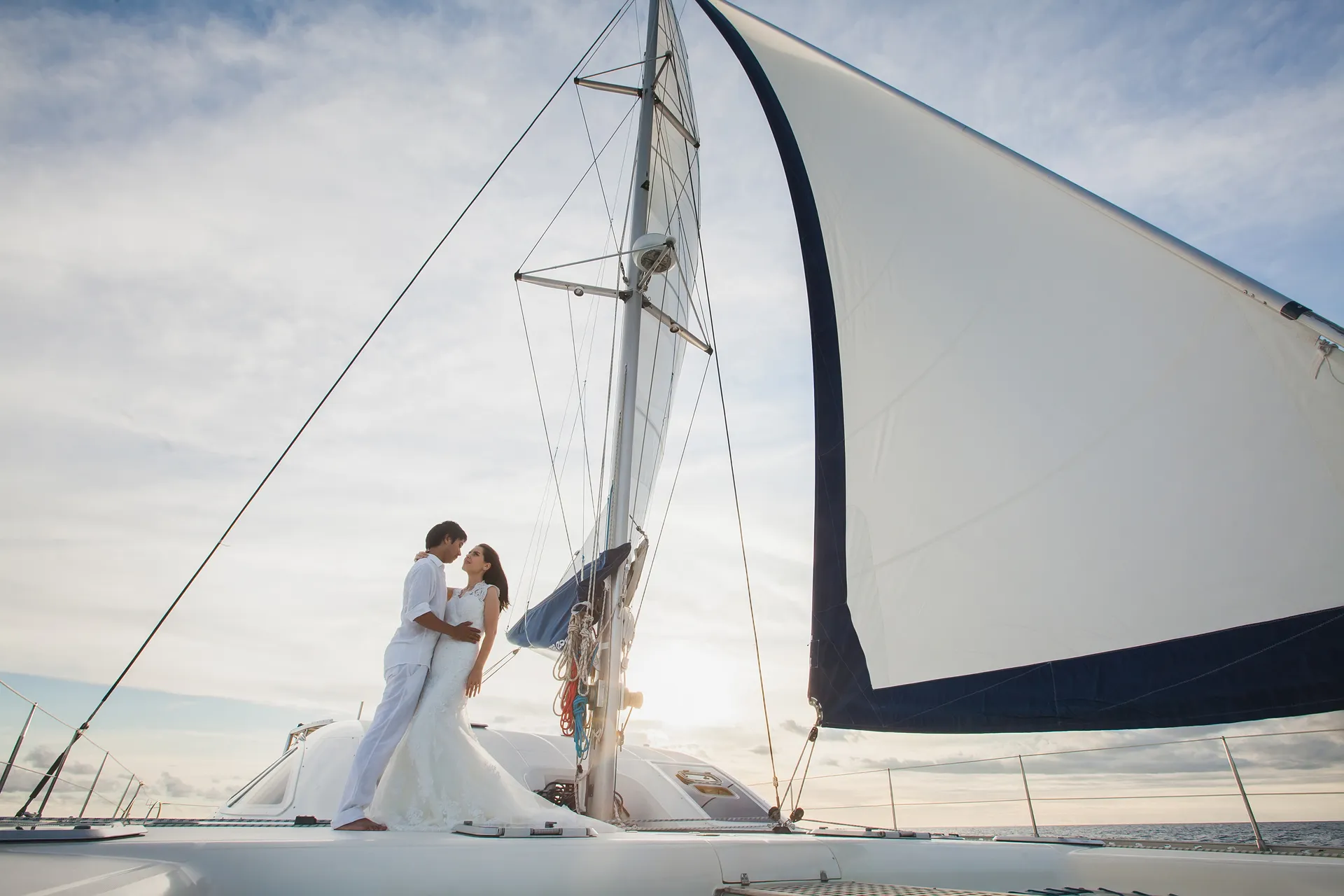 Schönes Hochzeitsbild: Braut und Bräutigam auf einer Yacht, die sich liebevoll auf dem offenen Meer küssen – eine stilvolle Marine-Hochzeit im Freien.