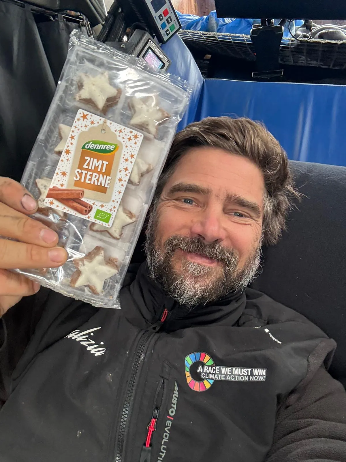 Boris Herrmann liegt entspannt an Bord der Malizia - Seaexplorer und hält eine Packung Zimtsterne in die Kamera – ein süßer Genuss während der Vendée Globe.