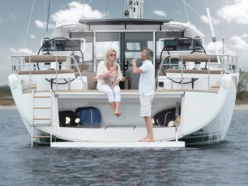 Ein entspanntes Ehepaar genießt ein Glas Wein auf der Badeplattform der Luxus-Segelyacht Moody 54 DS Freedom.