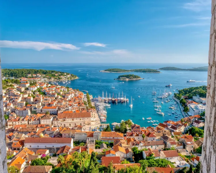 Panoramablick auf den Hafen von Hvar mit Segelyachten und den vorgelagerten Pakleni-Inseln im türkisblauen Wasser