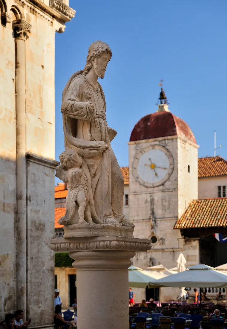 Statue am historischen Marktplatz in Trogir mit Blick auf den Uhrturm und mittelalterliche Gebäude