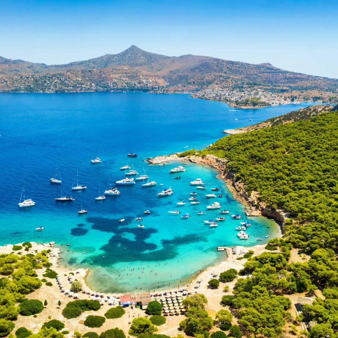 Segelyachten und Katamarane vor Anker in einer türkisfarbenen Bucht im Saronischen Golf, Griechenland