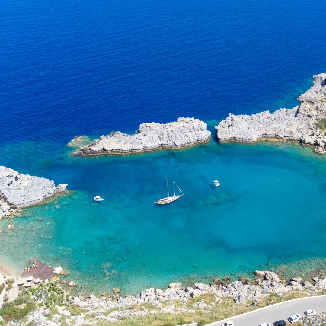 Segelboot vor Anker in einer geschützten Bucht mit türkisblauem Wasser bei Rhodos im Dodekanes, Griechenland