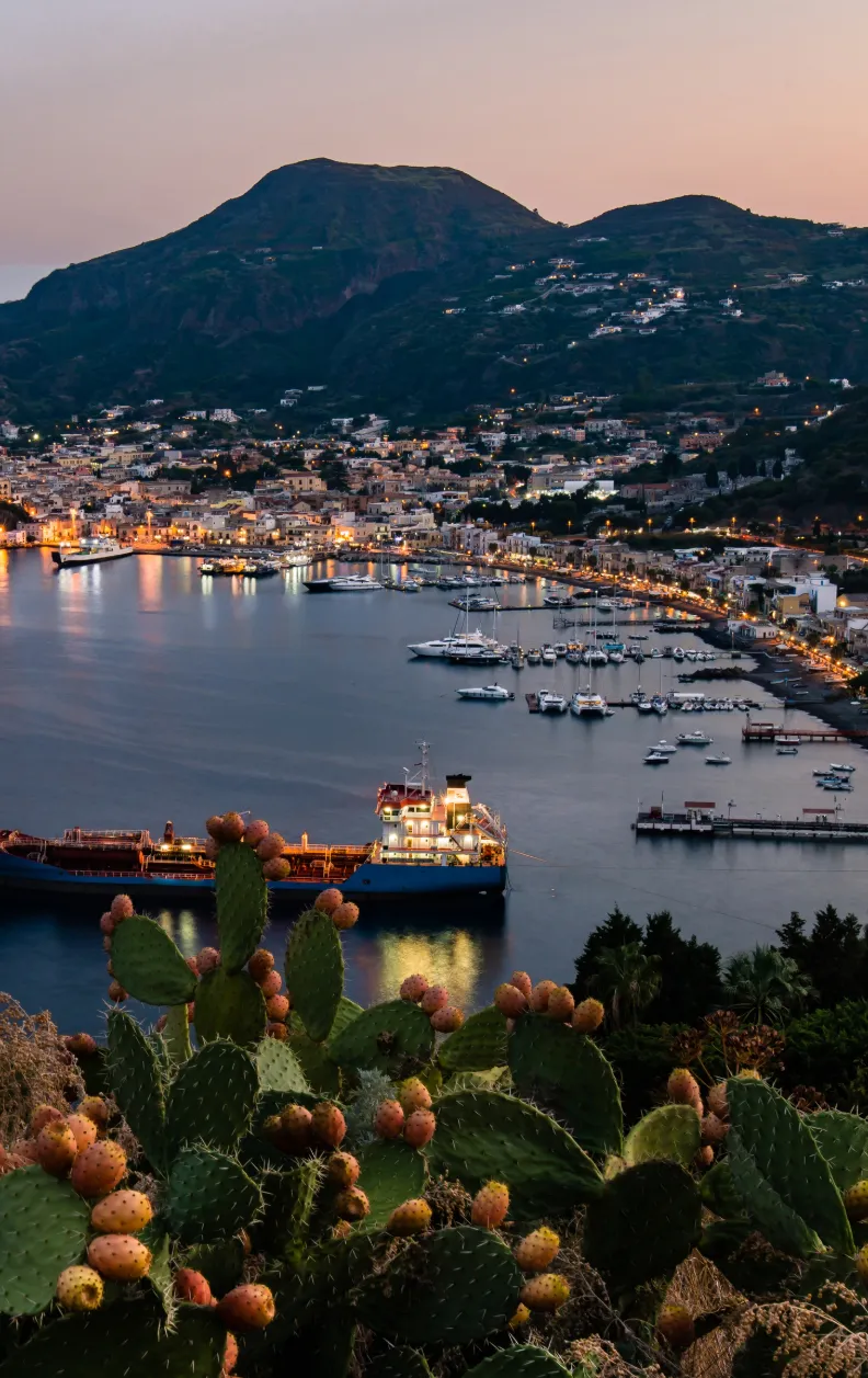 Blick auf die Marina und Altstadt von Lipari bei Sonnenuntergang mit Segelyachten im Hafen – Yachtcharter mit BlackSails-Yachting