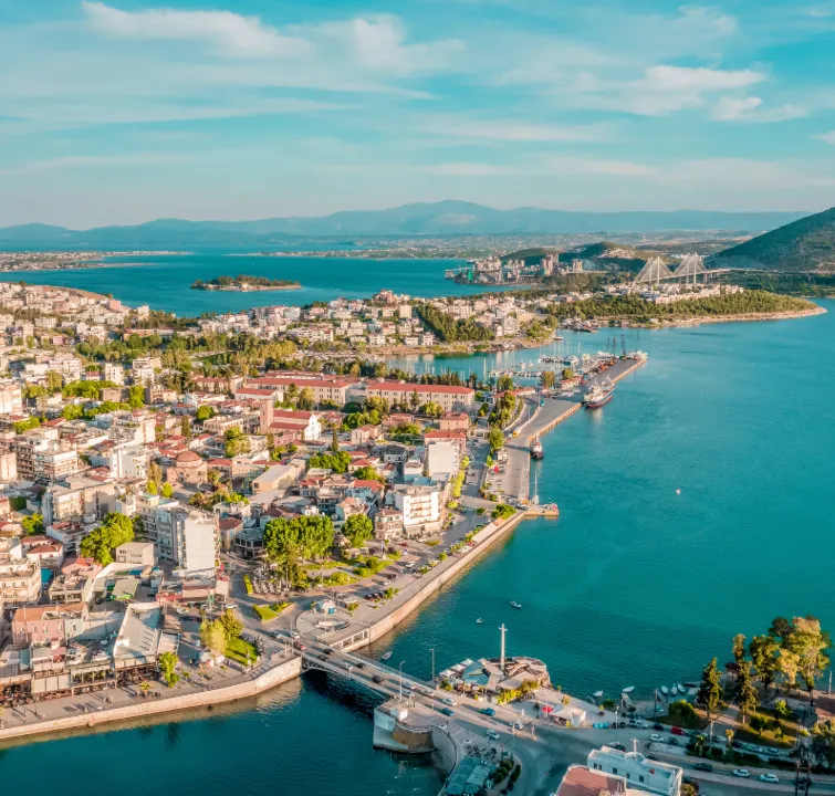 Luftaufnahme eines griechischen Küstenorts mit Hafenanlage, Brücken und türkisfarbenem Wasser – Start- oder Zwischenstation beim Yachtcharter mit BlackSails-Yachting.