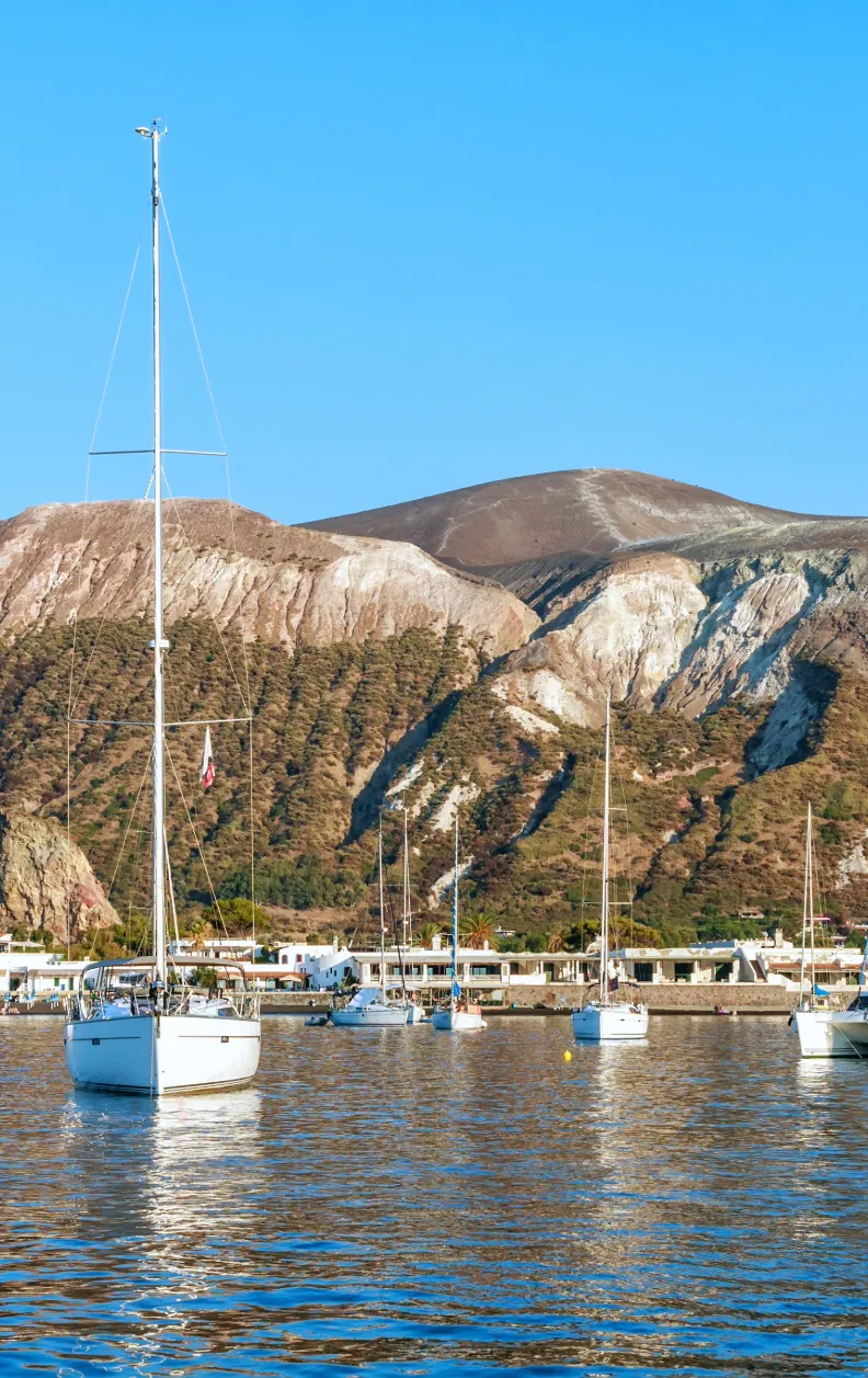 Mehrere Segelyachten vor Anker vor der Vulkaninsel Stromboli mit Sicht auf den Krater – Yachtcharter mit BlackSails-Yachting