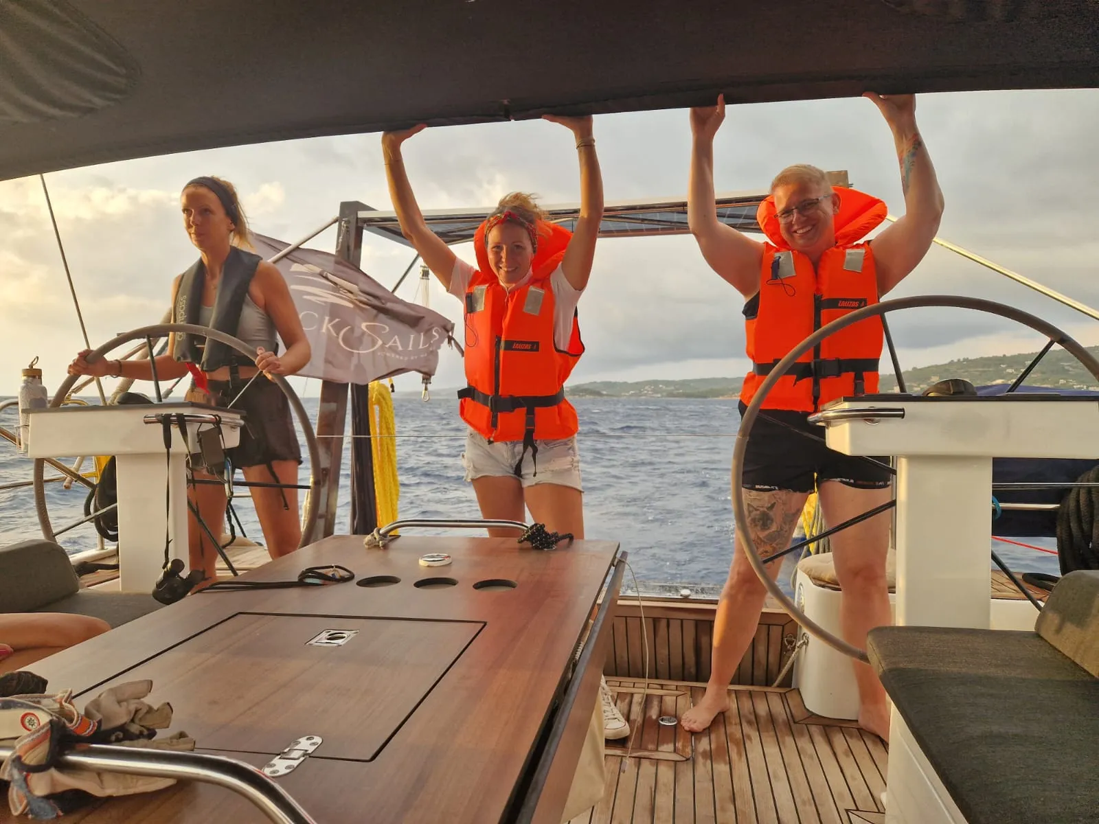 Laura mit zwei Frauen am Steuer der Segelyacht – alle mit Rettungsweste auf dem Rückweg von Paxos nach Korfu